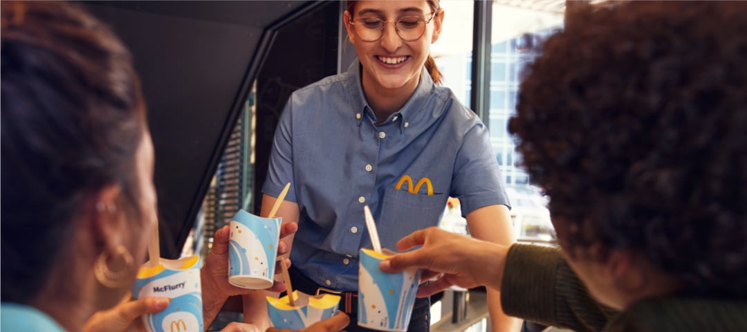 A McDonalds employee delivering food with a smile